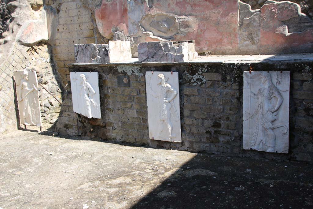 Herculaneum, April 2014. Sacred Area terrace, looking north in the shrine of the Four Gods.
The copies of the reliefs are thought to be hanging in their original position, fastened to the front wall of the podium. 
Photo courtesy of Klaus Heese.